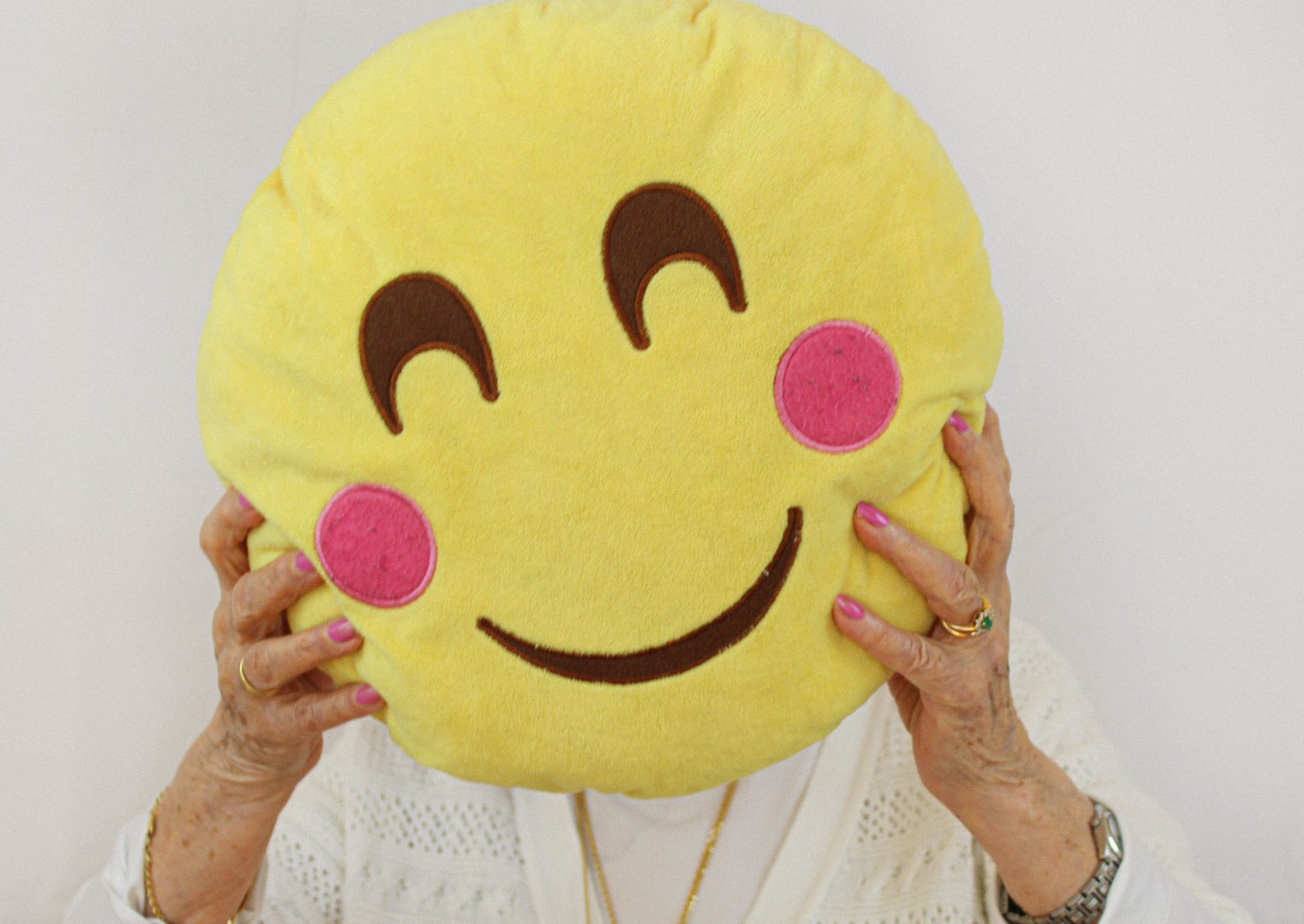 Photo d'une résidente avec un coussin en forme d'emoji qui sourit devant son visage